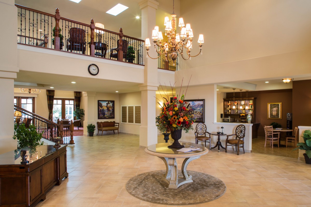 A spacious and elegantly decorated lobby with a chandelier, flowers, and modern furnishings.