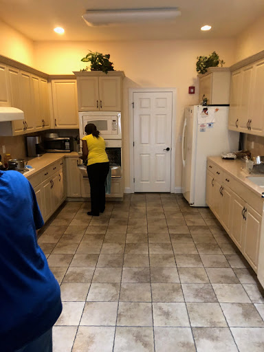 A spacious kitchen with modern appliances and two people engaged in activities.