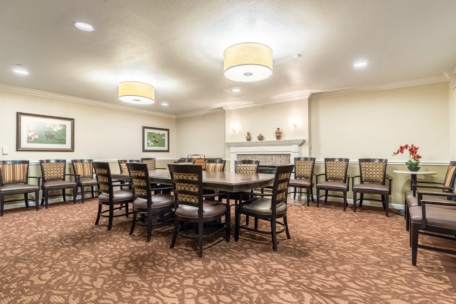 A well-lit conference room with a large table and multiple chairs arranged around it.