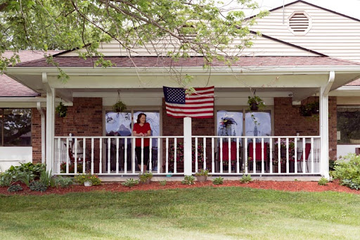 A welcoming porch adorned with an American flag, featuring people enjoying their time outdoors.