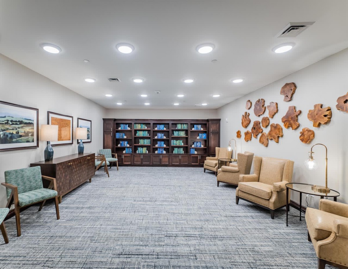 A modern waiting room featuring comfortable seating, decorative wall art, and neatly arranged shelves.