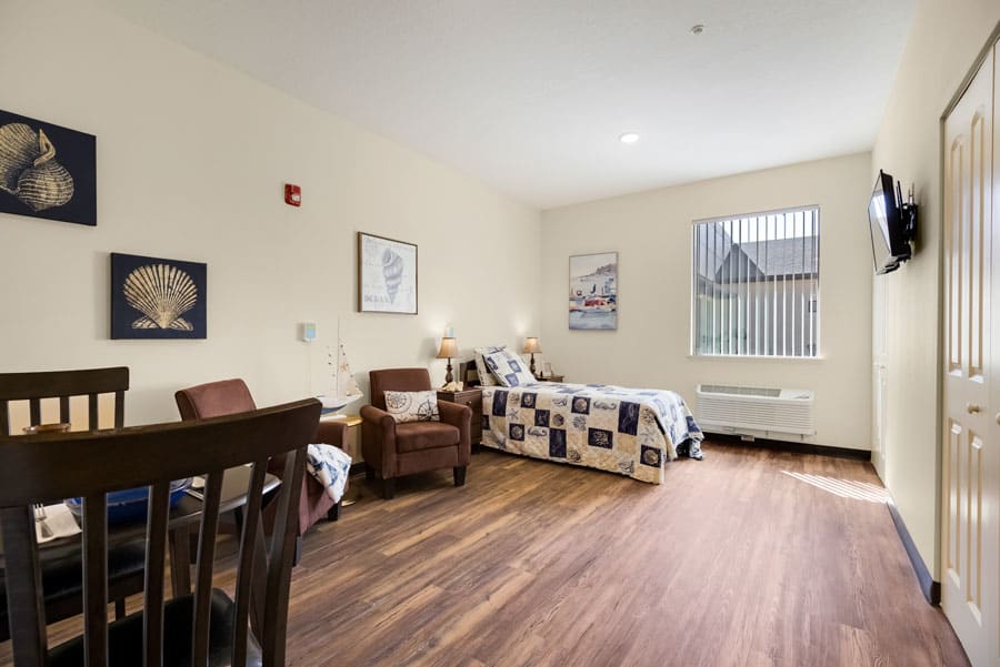 A cozy room with a single bed and comfortable chairs, featuring warm lighting and tasteful decor.