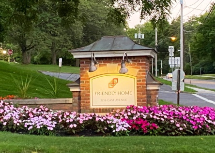 A welcoming entrance sign adorned with vibrant flowers.