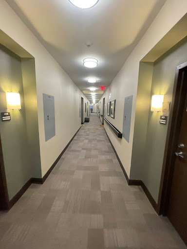 A long, well-lit hallway featuring multiple doors and a clean, modern interior.