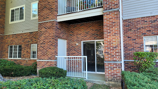A view of an apartment building featuring a brick facade and a balcony.