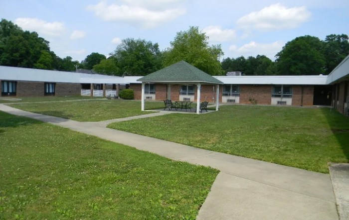 A peaceful outdoor area with a gazebo, surrounded by grass and a walkway.