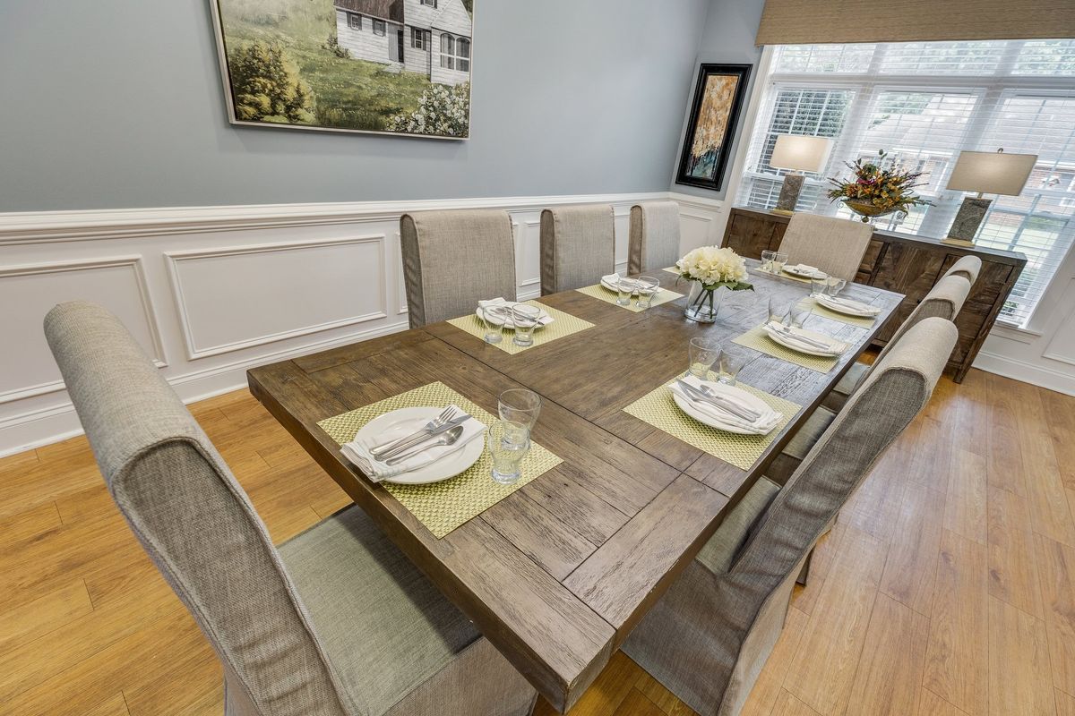 A modern dining room with a wooden table set for six, featuring elegant place settings and contemporary decor.