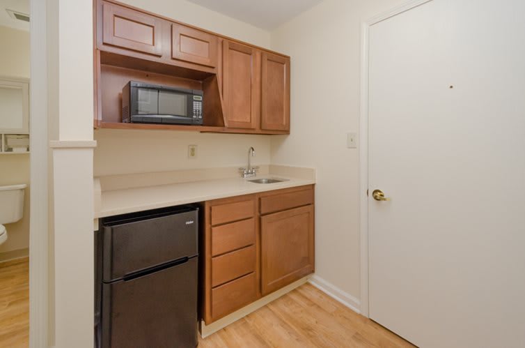 A compact kitchen area featuring wooden cabinets, a microwave, and a small sink.