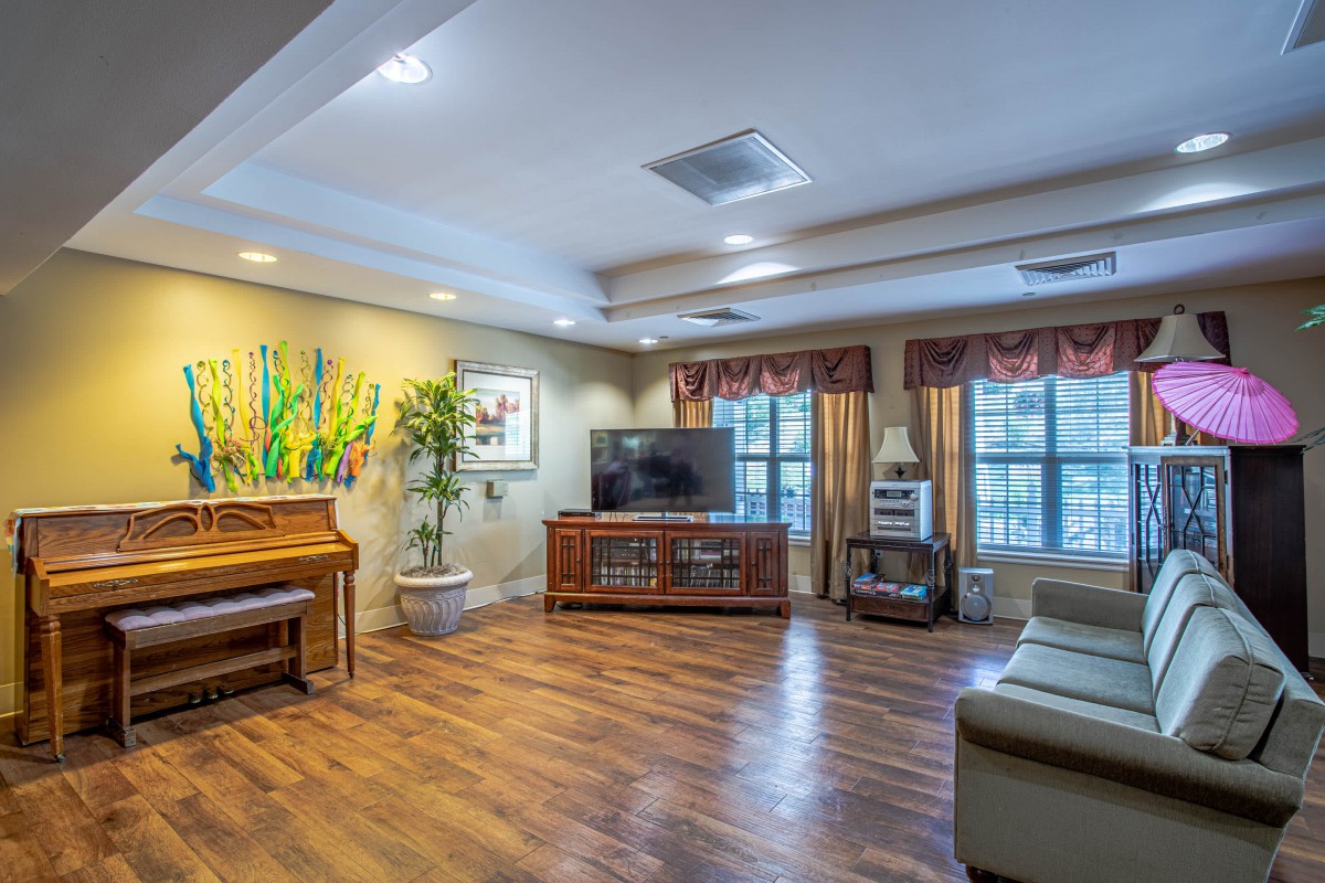 A cozy living room with a piano, TV, and comfortable seating.
