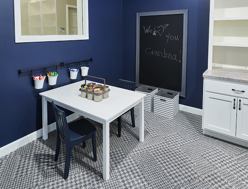 A cozy children's playroom featuring a blue wall, a white table with art supplies, and a chalkboard for creative expression.