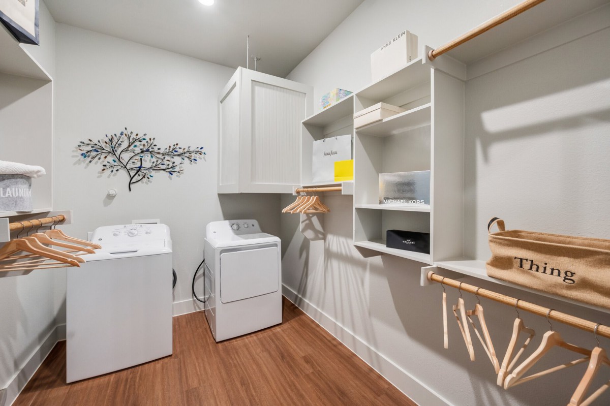 A tidy and organized laundry room featuring a washing machine and dryer with shelves for storage.