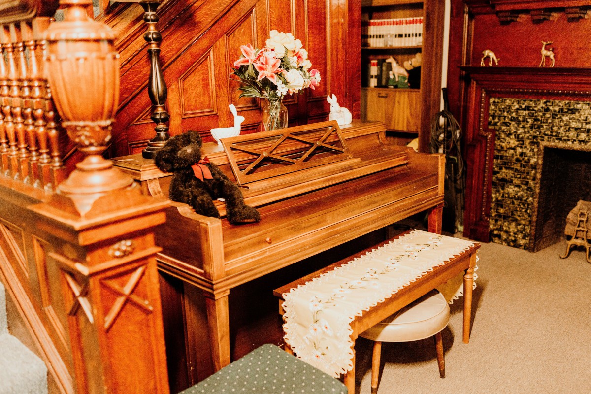 A cozy home setting featuring a wooden piano adorned with a flower arrangement and decorative objects.