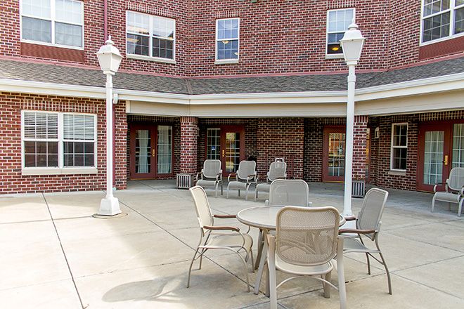 A patio area with chairs and a table outside a brick building.