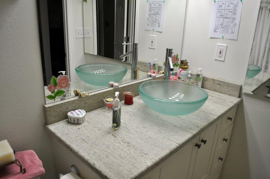 A modern bathroom with a glass bowl sink and vanity mirror.