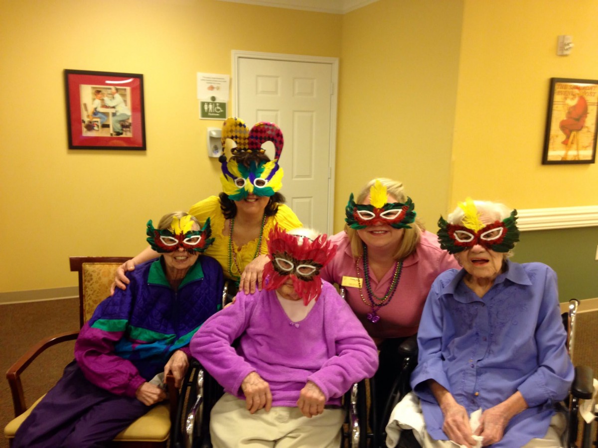 A group of people wearing colorful masks and costumes, celebrating indoors.