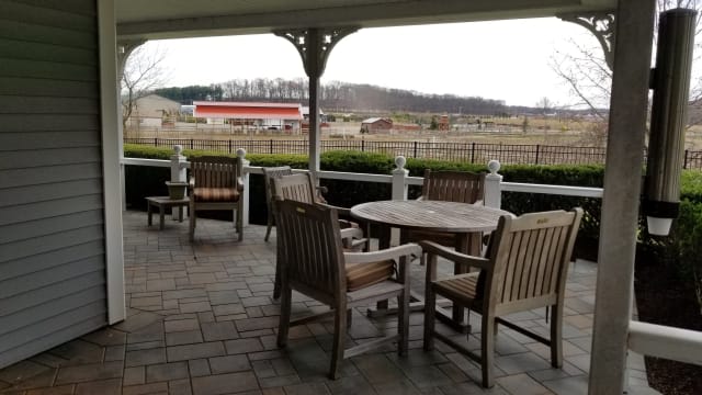 A cozy outdoor patio with wooden furniture overlooking a countryside farm.