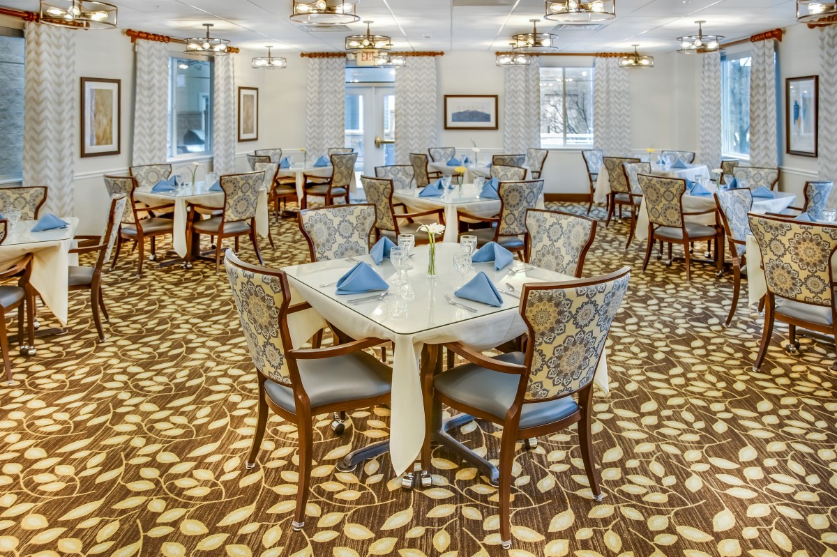 Elegant dining room with neatly set tables and patterned carpet.
