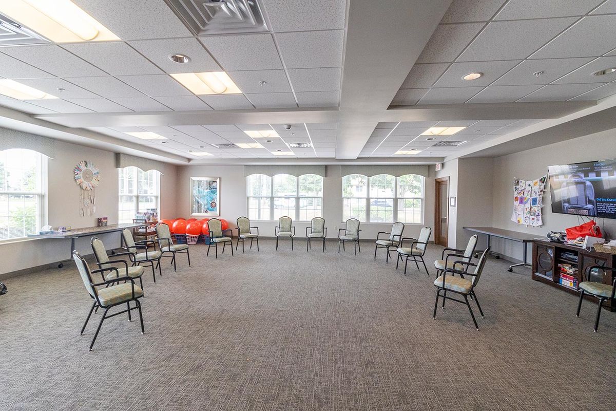 A well-lit meeting room with chairs arranged in a circle and large windows allowing natural light.