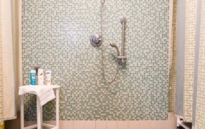 A modern bathroom with green tiled walls and a shower setup.