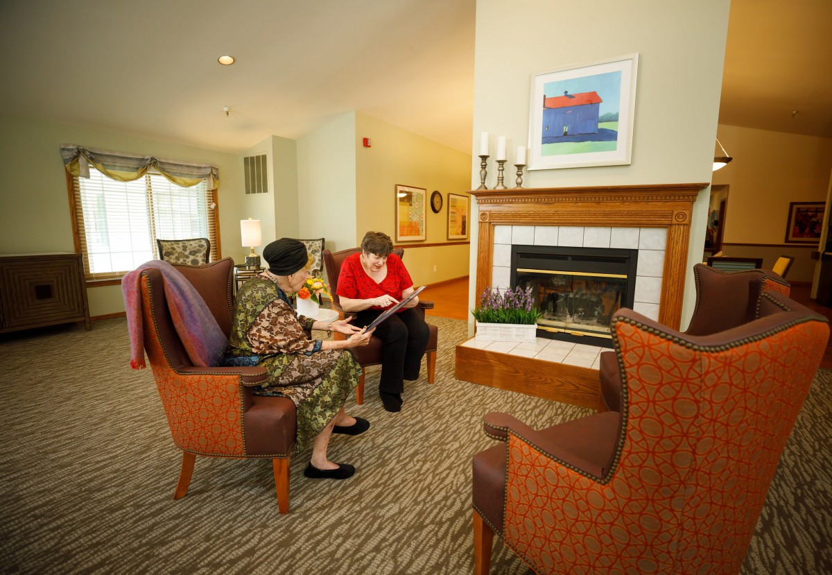 Two people sitting in a cozy living room, engaging in conversation near the fireplace.