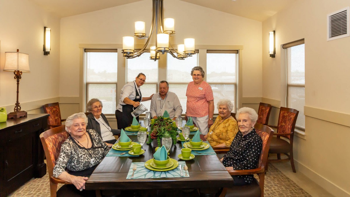 A group of people gathered around a dining table set for a celebration.