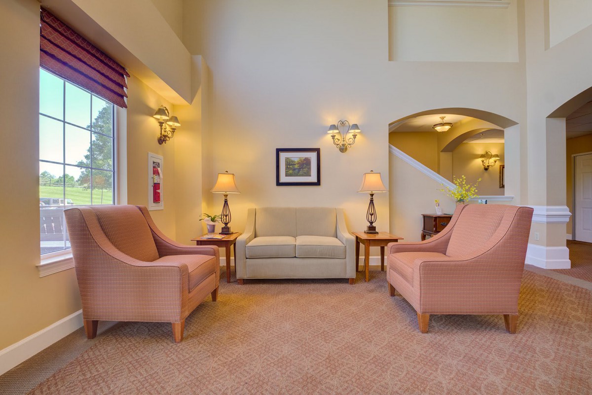 A cozy living room with matching sofas and armchairs, illuminated by elegant lamps.