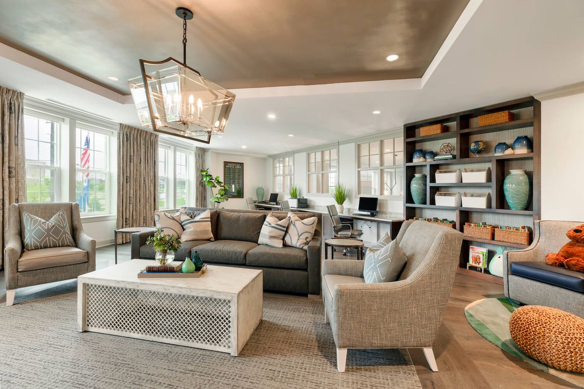 A modern living room featuring a large sofa, comfortable armchairs, a chic coffee table, and ample natural light from large windows.