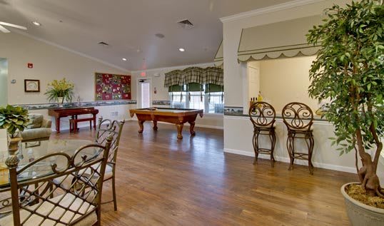 A spacious game room with a pool table, bar seating, and large windows.