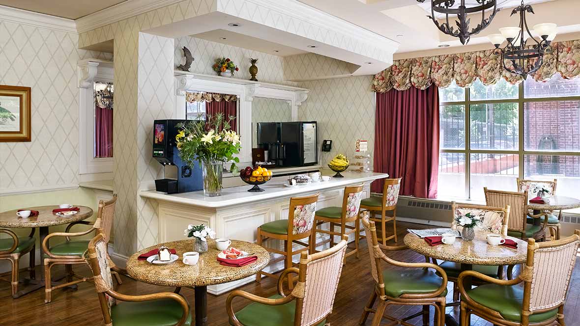 A cozy cafe interior with tables and chairs, decorated with flowers and a television.