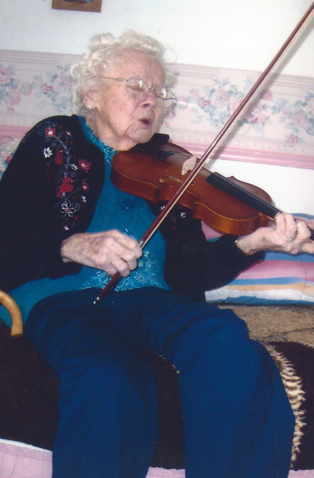 An elderly person playing the violin indoors.