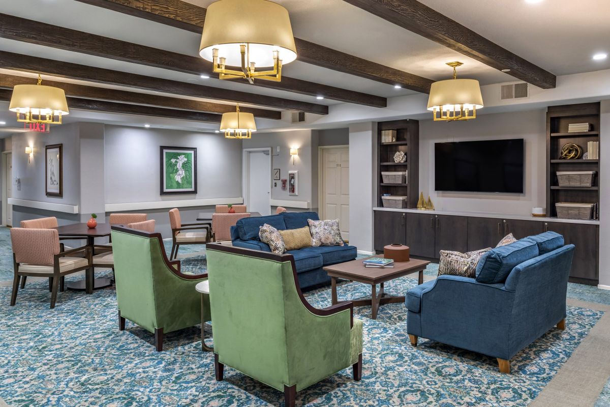 A cozy living room with colorful seating, decorative beams, and a large television.