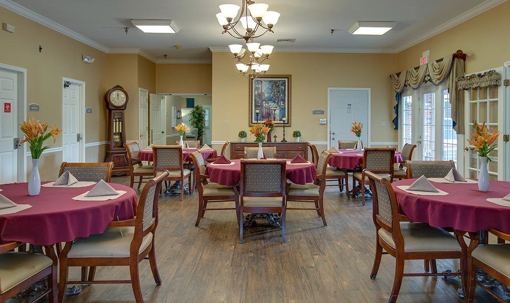 A cozy dining room with neatly arranged tables and chairs, featuring warm lighting and elegant decor.