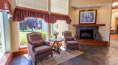 A cozy living room with two armchairs facing a fireplace, accompanied by a small round table and decorative elements.