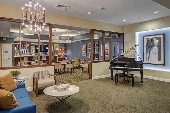 A modern lounge featuring a grand piano, comfortable seating, and elegant lighting.