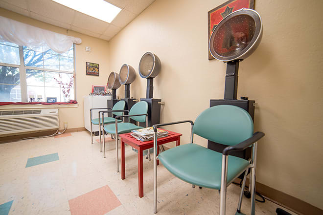 A cozy hair salon waiting area with dryers and comfortable seating.