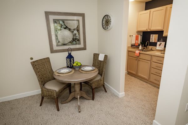 A cozy dining area with a small table and two chairs adjacent to a kitchen, featuring modern decor.