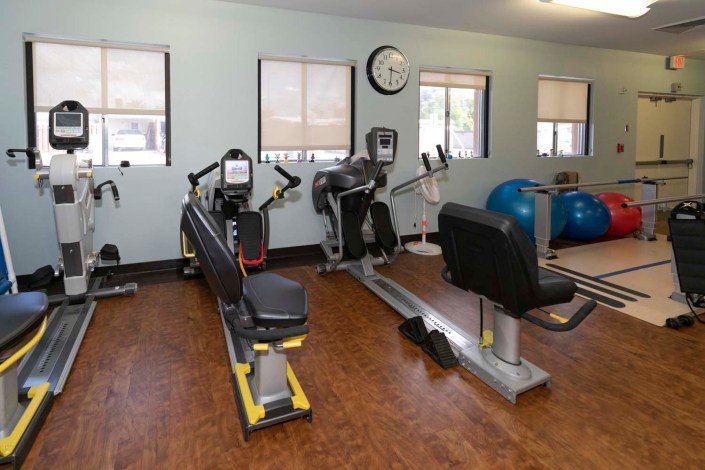 A fitness room equipped with various exercise machines including a rowing machine and stationary bike.
