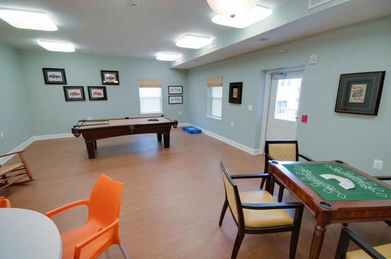 A recreational game room featuring a pool table and a card table with chairs.
