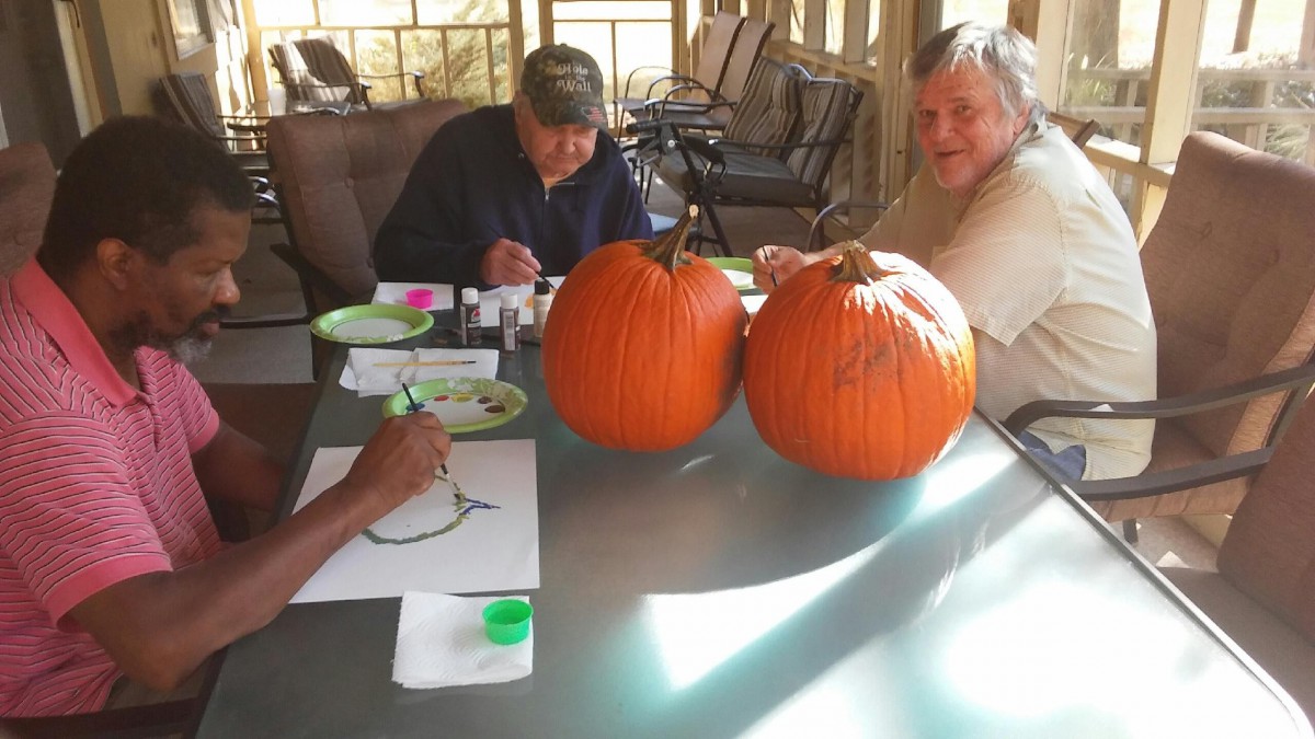 Seniors enjoying a pumpkin painting activity outdoors.