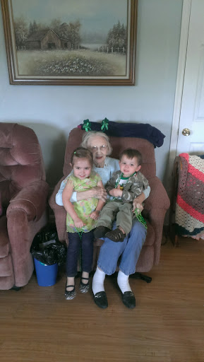 A heartwarming moment of family bonding, featuring two children sitting on the lap of an elderly relative.
