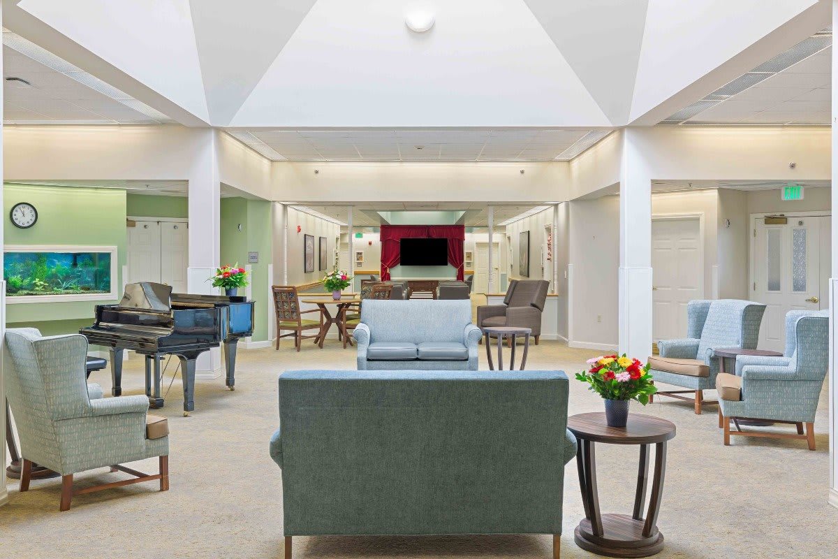 A spacious and well-lit lobby area with comfortable seating and a piano.