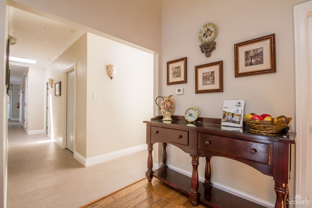 A warmly lit hallway featuring a wooden console table adorned with decorative items and framed artwork on the wall.