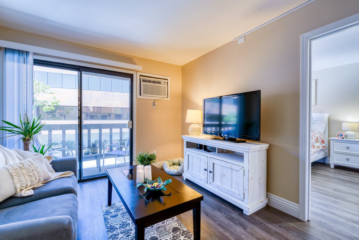 A cozy living room with modern decor, featuring a TV on a white stand, a coffee table, and a plush sofa.