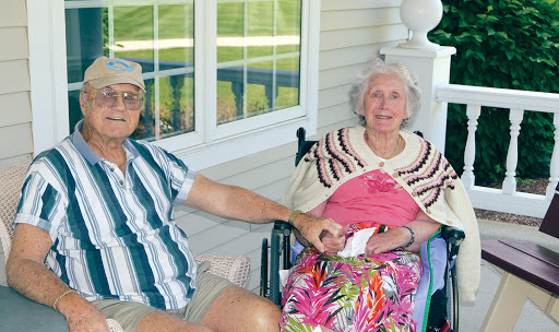 An elderly couple enjoying a sunny day on their porch, sharing a moment of affection.
