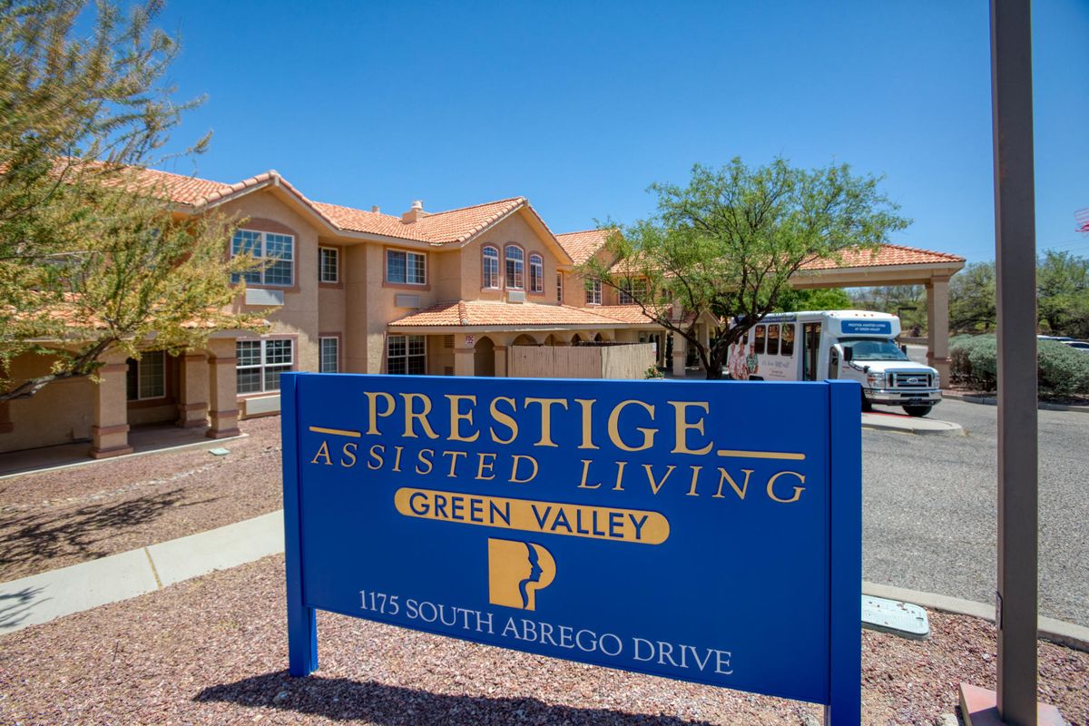 A sign for Prestige Assisted Living in front of a residential building.