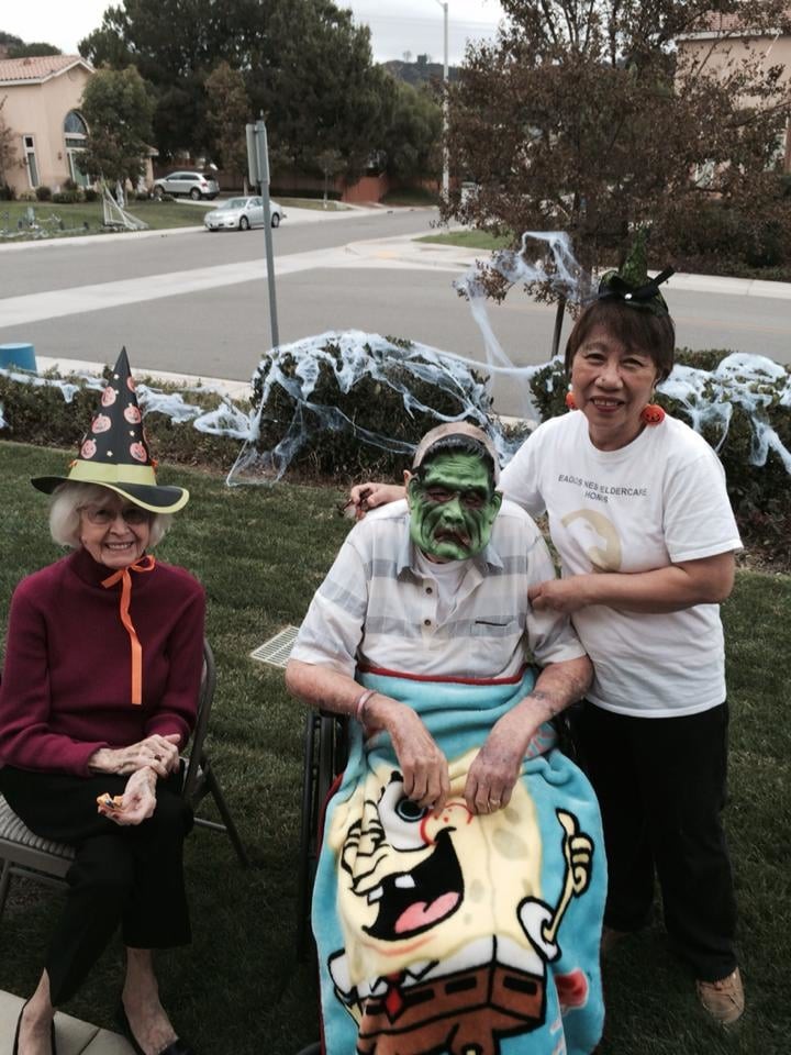 A group of people in Halloween costumes, photographed outdoors with festive decorations.