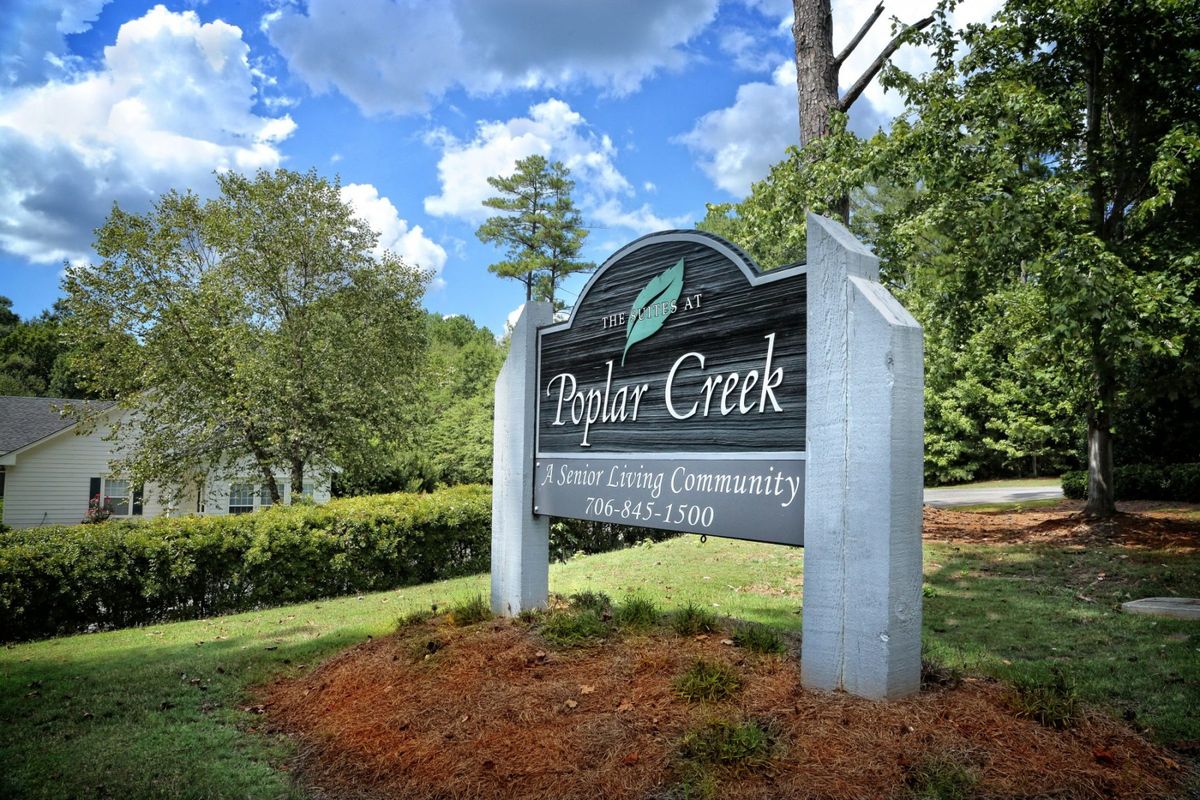 Entrance sign for Poplar Creek surrounded by trees and greenery.