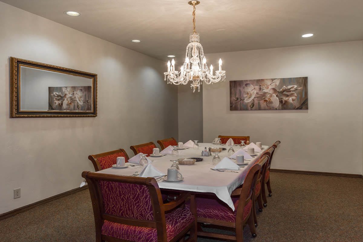 An elegantly set dining room table with a chandelier overhead.