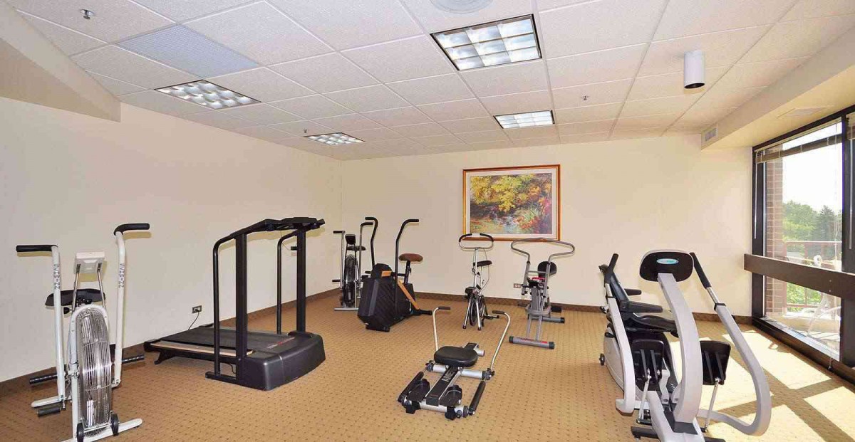 A small gym with various exercise equipment including a treadmill and stationary bikes.