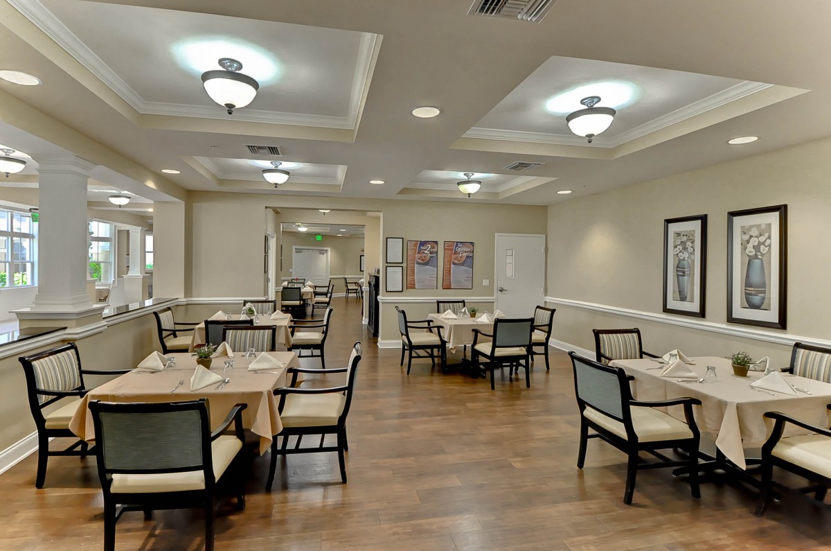 A well-lit dining room with neatly arranged tables and chairs, showcasing a comfortable and elegant interior design.